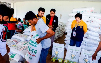 <p><strong>GOVERNMENT AID</strong>. A farmer carries a sack of fertilizer as Tacurong City Vice Mayor Lina Montilla (right) looks on. The farmer is among the 101 corn farmers who received corn seeds and fertilizers from the Department of Agriculture–Soccsksargen Region and the city government on Tuesday (June 6, 2023). <em>(Photo courtesy of DA-12)</em></p>
