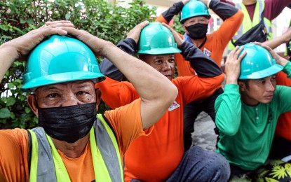 <p><strong>QUAKE PREPAREDNESS. </strong>Workers at the Quezon City Hall do the "duck, cover and hold" gesture during the 2023 2<sup>nd</sup> Quarter National Simultaneous Earthquake Drill (NSED) in this photo taken on June 8, 2023. Defense Secretary and National Disaster Risk Reduction and Management Council chair Gilberto Teodoro Jr., earlier urged the public to take the NSED seriously as this would help save lives during a major earthquake. <em>(PNA file photo by Joan Bondoc)</em></p>