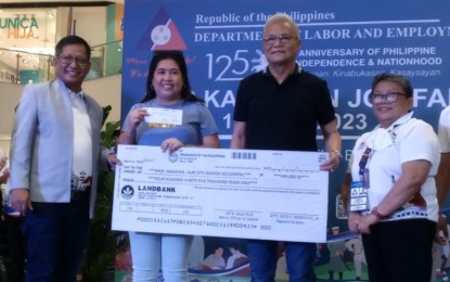 <p><strong>AID FOR WORKERS</strong>. Department of Labor and Employment in Western Visayas Director Sixto Rodriguez Jr. (left) and Negros Occidental Field Office head Carmela Abellar (right) turn over a PHP495,000 check to village treasurer Elizabeth Cordero and chief Henry Belleza of Barangay Hawaiian, Silay City in Negros Occidental as assistance under the Tulong Panghanapbuhay sa Ating Disadvantaged/Displaced Workers. A total of 16 barangays in the cities of Silay and Bacolod received PHP5.553 million in cash aid during the program for the 2023 Kalayaan Job Fair and World Day Against Child Labor held at SM City Bacolod on Monday (June 12, 2023). <em>(PNA photo by Nanette L. Guadalquiver)</em></p>