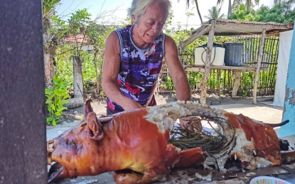 <p><strong>ROAST PIG</strong>. A resident in Negros Oriental chops down a lechon or roast pig in this undated photo, as provincial authorities reiterate it is safe to eat pork dishes despite African swine fever cases being reported in the province. The capital city, Dumaguete, has reported its first case and is now undertaking monitoring and surveillance measures to contain the spread of the disease. <em>(PNA photo by Judy Flores Partlow)</em></p>