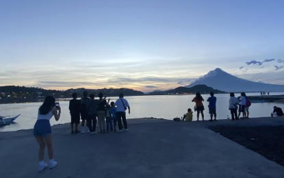 <p><strong>‘FURIOUS BEAUTY’</strong>. A family poses for a photo shoot with Mayon Volcano as background at the Legazpi Boulevard shortly after sunset on Monday (June 12, 2023). The Albay Provincial Tourism, Culture and the Arts Office (PTCAO) has recommended viewing sites for all visitors who want to watch and document the 'fury' of Mayon Volcano. <em>(PNA photo by Connie Calipay)</em></p>