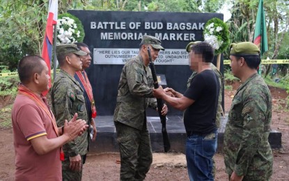 <p><strong>SURRENDER.</strong> An Abu Sayyaf Group member identified only as Tigong (in black shirt) hands over a Garand rifle when he was presented to Maj. Gen. Ignatius Patrimonio, commander of the Army’s 11th Infantry Division (ID), in Bud Bagsak, Talipao, Sulu on Thursday (June 15, 2023). Tigong, 41, who joined the ASG in 2011, surrendered to the troops of the 2nd Special Forces Battalion in Talipao town. <em>(Photo courtesy of 11ID)</em></p>
