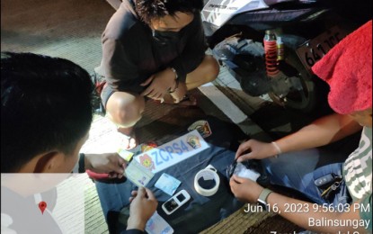 <p><strong>DRUG HAUL</strong>. Undercover policemen conduct an inventory in front of the arrested suspect (center) on the pieces of evidence seized in an anti-drug operation that netted P340,000 worth of suspected shabu in Barangay Talabaan, Zamboanga City on Friday night (June 16, 2023). The police have arrested 16 suspects and seized over P1.7 million worth of illegal drugs in separate operations in Zamboanga Peninsula from June 1 to 16. <em>(Photo courtesy of Zamboanga City Police Office Station 4)</em></p>