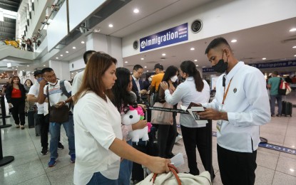 <p><strong>NOT REQUIRED.</strong> An airport personnel checks the passport of a passenger at the NAIA in this undated photo. The Department of Health said arriving international travelers are allowed entry regardless of their vaccination status for the coronavirus disease 2019. <em>(PNA photo by Yancy Lim)</em></p>