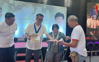 <p><strong>TITLE HOLDER. </strong>Presidential Assistant (PA) for Eastern Mindanao Secretary Leo Magno hands over the land title certificate to an agrarian reform beneficiary on Friday (July 7, 2023) in Davao City. Coinciding with the signing of the New Agrarian Emancipation Act by President Ferdinand R. Marcos Jr., the Department of Agrarian Reform in Davao Region distributed electronic titles to 789 agrarian reform beneficiaries.<em> (PNA photo by Robinson Niñal Jr.)</em></p>