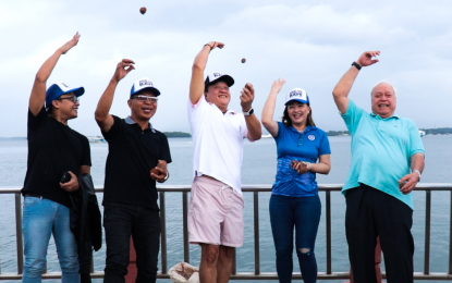 <p><strong>MUDBALLS PITCH</strong>. Puerto Princesa Mayor Lucilo Bayron (right) leads the ceremonial tossing of mudballs into the city bay to launch the "Save the Puerto Princesa Bays" project on Saturday (July 15, 2023). The mudballs contain microorganisms that will hasten the recovery of the marine ecosystem. <em>(Photo from Puerto Princesa-CIO)</em></p>