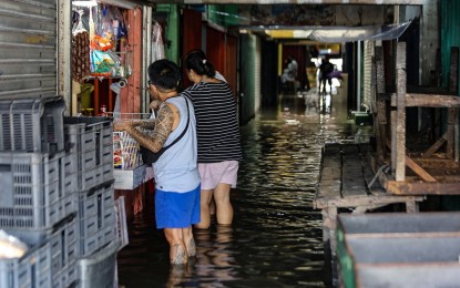 <p><strong>FLOODED.</strong> Residents buy goods from a stall inside the flooded Guagua Public Market in Pampanga on July 30, 2023. The National Disaster Risk Reduction and Management Council on Tuesday (Aug. 1, 2023) said the amount of damage to agriculture and infrastructure caused by the Typhoon Egay and the southwest monsoon has reached over PHP5.4 billion. <em>(PNA photo by Joan Bondoc)</em></p>
