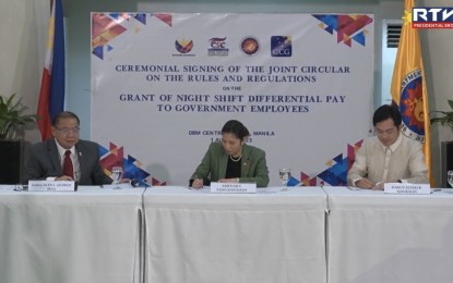 <p><strong>NIGHT DIFFERENTIAL PAY.</strong> A joint circular on the rules and regulations on the grant of the night differential pay to government employees is signed in a ceremony held at the main office of the Department of Budget and Management (DBM) on Tuesday (Aug. 1, 2023). The joint circular was signed by DBM Secretary Amenah Pangandaman (middle), Civil Service Commission chairperson Karlo Alexei Nograles (right) and Governance Commission for GOCCs chairperson Alex Quiroz (left). <em>(Screenshot from Radio Television Malacañang)</em></p>