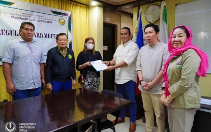 <p>APPROVED INVESTMENT. Members of the Bangsamoro Board of Investments (BBOI), led by chairperson Mohammad Pasigan (3rd from right), present the certificate of registration of new investments to Liezlda Ansing representing the investor – Illana Bay Resort – after the board’s approval on Aug. 2, 2023. The BARMM, which targets PHP2.5 billion worth of investments this year, has surpassed its target by achieving PHP3.1 investments to date. (Photo courtesy of Bangsamoro Information Office-BARMM)</p>