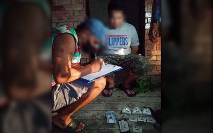 <p><strong>BUSTED.</strong> A police operative makes an inventory of the illegal drugs seized from suspect Alibsar Macarangkat Macasari (right) in an early morning drug bust in Lucena City on Wednesday (Aug. 9, 2023). Confiscated from the suspect is PHP8.2 million worth of suspected shabu. <em>(Photo courtesy of Quezon Provincial Police Office)</em></p>