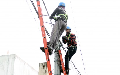 <p><strong>SAFETY.</strong> Two linemen connect a cable wire to a post along Mindanao Avenue in Quezon City on Aug. 16, 2023. The House of Representatives on Wednesday (Aug. 7, 2024) approved on second reading a measure proposing the safe installation and maintenance of overhead electrical distribution, cable, and communications lines. <em>(PNA photo by Jess M. Escaros Jr.)</em></p>