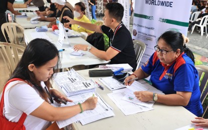 <p><strong>ASPIRING OFW.</strong> An aspiring overseas Filipino worker fills up the necessary forms during the overseas job fair at the Quezon City Hall Risen Garden on Friday (August 18, 2023). Over 3,000 land-based and sea-based overseas jobs were offered at the job fair organized by the Quezon City government, in partnership with the Department of Migrant Workers. <em>(Photo courtesy of QC LGU)</em></p>