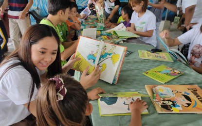 <p><strong>AGRI-LITERACY.  </strong>Students of Calasiao Comprehensive National High School, who are members of the 4-H Pinablic Calasiao group, read books to children in Barangay Buenlag, Calasiao, Pangasinan in this undated photo. The activity is part of the Project Aral of the group that aims to teach children of Pantawid Pamilya Pilipino Program beneficiaries on reading and writing as well as some basic knowledge on agriculture. <em>(Photo courtesy of 4-H Pinablin Calasiao)</em></p>
