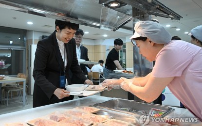 <p>Senior presidential secretary for press affairs Kim Eun-hye (L) is served a tray of sliced raw fish at the in-house cafeteria of the presidential office in Seoul on Aug. 28, 2023, in this photo provided by the office.  <em>(Yonhap)</em></p>