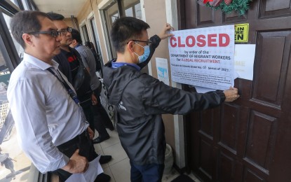 <p><strong>PADLOCKED</strong>. Department of Migrant Workers Officer-in-Charge Undersecretary Hans Leo Cacdac (wearing black long sleeves) leads the closure of  RTM Maritime Consultancy Services Corp in Parañaque City on Thursday (Sept. 7, 2023).  Cacdac said the agency offered fake jobs abroad. <em>(PNA photo by Yancy Lim) </em></p>