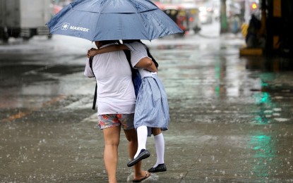 <p><strong>YOU ARE SAFE WITH ME.</strong> Under a big umbrella and with her mother tightly carrying her, a young student will get home safe and dry amid a downpour on Tuesday (Sept. 12, 2023). The southwest monsoon or "habagat" will continue to bring rain showers in most areas in the country on Thursday (Sept. 14), the weather bureau said. <em>(PNA photo by Joan Bondoc)</em></p>