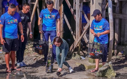 <p><strong>COASTAL CLEAN UP.</strong> Tourism Secretary Christina Garcia-Frasco picks up a  rubbish as she joined local government officials in a coastal clean-up drive at Mactan Newtown Beach in Lapu-Lapu City, Cebu on Friday (Sept. 15, 2023). The activity was held a day after Frasco led the three-day Philippine Tourism Dive Dialogue at Nustar Hotel and Resort in Cebu City that culminated Thursday. <em>(Photo courtesy of Lapu-Lapu City PIO)</em></p>