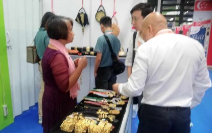 <p><strong>TRADE.</strong> Milagros Berboso Imson of KitSilver Jewellery introduces her creations to her clients during the 20th China-Association of Southeast Asian Nations Expo at the Philippine National Pavilion of the Nanning International Exhibition and Convention Center in Nanning, Guangxi on Saturday (Sept. 16, 2023). Victoria Arellano of the Department of Trade and Industry-Center for International Trade Expositions and Missions said the 15 exhibitors from the  Philippines are optimistic about regaining their lost investors. <em>(PNA photo by Annabel Consuelo J. Petinglay)</em></p>