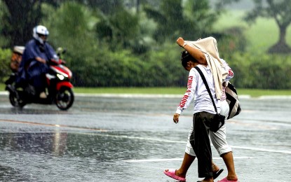 <p><strong>TAKE COVER.</strong> A couple shares a single jacket being caught unprepared by the sudden downpour at the University of the Philippines Diliman in Quezon City on Sunday afternoon (Sept. 17, 2023). Most parts of the country will experience rain showers due to the southwest monsoon (<em>habagat)</em> and localized thunderstorms, the weather bureau said Tuesday (Sept. 26, 2023). <em>(PNA photo by Joan Bondoc)</em></p>