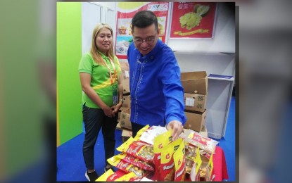 <p><strong>BEST SELLER.</strong> Department of Trade and Industry (DTI) Undersecretary Dr. Ceferino S. Rodolfo (right) checks on the remaining durian candies of the Eng Seng Food Products Company, one of the exhibitors from the Philippines at the 20th China-ASEAN Expo (CAEXPO) exhibition in Nanning in China on Monday (Sept. 18, 2023). Rodolfo on Tuesday (Sept.19, 2023) said fresh durian fruit is the best seller export commodity during the Sept. 16-19 expo. (<em>PNA photo by Annabel Consuelo J. Petinglay</em>)</p>