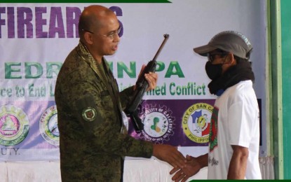 <p><strong>SURRENDER.</strong> A former combatant of the Communist Party of the Philippines-New People's Army hands over his firearm to Brig. Gen. Orlando Edralin, commander of the Philippine Army's 303rd Infantry Brigade, in rites held at the 79th Infantry Battalion headquarters in Sagay City, Negros Occidental on Friday (Sept. 29, 2023). He is one of the 12 rebels under the dismantled NPA Northern Negros Front who surrendered to the authorities in recent months. (<em>Photo courtesy of 79th IB, Philippine Army</em>)</p>