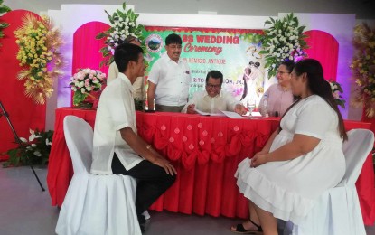 <p><strong>MASS WEDDING.</strong> Municipality of San Remigio Mayor Margarito Mission, Jr. (center) signs the marriage certificate of a newly married couple witnessed by Antique board member Rony Molina (second from left) and his wife Elena (fourth from left) on Wednesday (Oct.4, 2023). Mission said the ceremony is free for couples who have not yet been legally married due to accessibility and financial constraints. (<em>PNA photo by Annabel Consuelo J. Petinglay</em>)</p>