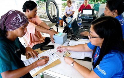 <p><strong>CONTINUING REGISTRATION.</strong> Philippine Identification System staff Lea Ngo (right) checks the documents of a national ID applicant at the Quezon City Hall grounds on Oct. 11, 2023. The Philippine Statistics Authority and the Department of Social Welfare and Development partnered up to bring the services of the Philippine Identification System to the Family Development Session of Pantawid Pamilyang Pilipino Program beneficiaries. <em>(PNA file photo by Ben Briones)</em></p>