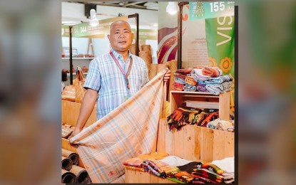 <p><strong>‘PATADYONG’.</strong> Mario Manzano, the chairperson of the Bagtason Loom Weavers Association in Bagtason, Bugasong, shows the naturally dyed patadyong or the handwoven rectangular wrap-around skirt they brought to the National Arts and Craft Fair in Metro Manila on Oct. 4-8, 2023. Manzano said in an interview Friday (Oct. 13) that aside from selling their products, they also established a network during the fair. (<em>Photo courtesy of Mario Manzano</em>)</p>