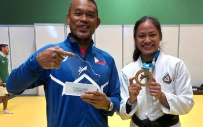 <p><strong>WINNER.</strong> Ju-jitsu fighter Kaila Jenna Napolis (right) holds the gold medal she won in the 2023 World Combat Games at the King Saud University Arena in Riyadh, Saudi Arabia on Oct. 25, 2023. With her is national coach John Baylon, a nine-time SEA Games judo gold medalist<em>. (Photo courtesy of Rhett Bettin)</em></p>