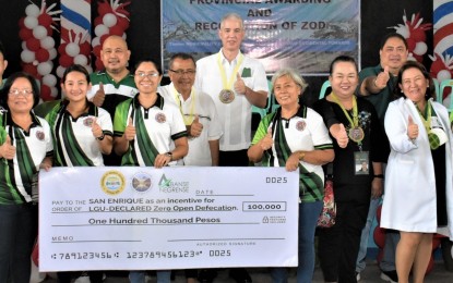 <p><strong>ZOD STATUS INCENTIVE</strong>. Negros Occidental Governor Eugenio Jose Lacson (center) and provincial health officer Dr. Ma. Girlie Pinongan (right) led the turn-over of the symbolic check worth PHP100,000 as cash incentive to the municipality of San Enrique led by Mayor Jilson Tubillara (5th from left) for having achieved a zero open defecation (ZOD) status, in rites held at the town gymnasium on Monday (Nov. 13, 2023). All households in 10 barangays of San Enrique already have access to toilets. (<em>Photo courtesy of PIO Negros Occidental</em>)</p>