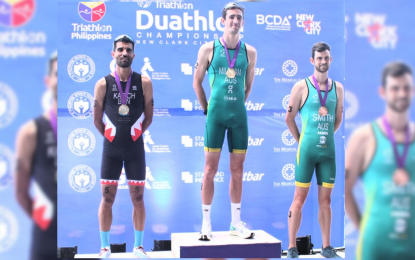 <p><strong>TOP THREE.</strong> Australian Samuel Mileham (center) is crowned men's elite champion of the 2023 Asia Triathlon Duathlon Championships at New Clark City Sports Complex in Capas, Tarlac on Sunday (Nov. 26, 2023). With him on the podium are silver medalist Moussa Karich of Bahrain (left) and bronze medalist Matt Smith of Australia. (<em>PNA photo by Jean Malanum)</em></p>