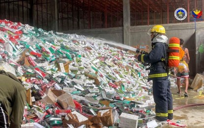 <p><strong>DESTROYED.</strong> A firefighter from the Bureau of Fire Protection (BFP) sprays water on contraband cigarettes worth PHP323 million at a warehouse rented by the Bureau of Customs (BOC) in Barangay Tetuan, Zamboanga City on Thursday (Nov. 30, 2023). The cigarettes, which were seized from May to November this year, were subsequently crushed by payloader equipment and then disposed of in the sanitary landfill in Barangay Salaan, Zamboanga City.<em> (Photo courtesy of BOC-Port of Zamboanga)</em></p>