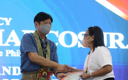 <p><strong>LAND OWNERSHIP.</strong> President Ferdinand R. Marcos Jr. turns over a land title to an agrarian reform beneficiary at the City of Passi Arena in Iloilo province on Monday (Dec. 11, 2023). Marcos ordered the Department of Agrarian Reform to complete the land distribution to deserving beneficiaries. <em>(PNA photo by Alfred Frias)</em></p>