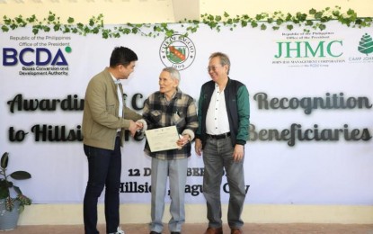 <div dir="auto"><strong>ALMOST THERE</strong>. Bases Conversion and Development Authority president and chief executive officer Joshua Bingcang (left) and John Hay Management Corporation president Allan Garcia award the Certificate of Recognition to 97-year-old Eduardo Damatac of Barangay Hillside during a program in Camp John Hay, Baguio City on Tuesday (Dec. 12, 2023). The certificate recognizes the recipient as the future rightful owner of the land within the Camp John Hay reservation.<em> (Photo courtesy of BCDA)</em></div>
