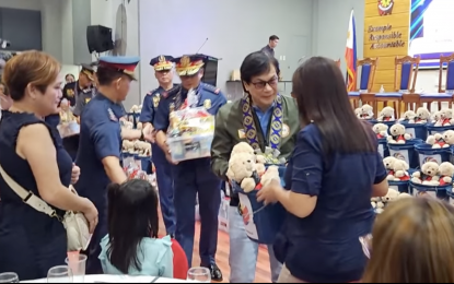 <p><strong>GIFT-GIVING</strong>. Interior Secretary Benhur Abalos hands out a Christmas pack during a gift-giving activity at Camp Bagong Diwa in Taguig City on Saturday (Dec. 16, 2023). A total of 193 relatives of 104 fallen members of the Philippine National Police, Bureau of Jail Management and Penology and Bureau of Fire Protection received gifts. <em>(Screengrab from PNP video)</em></p>