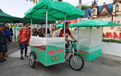 <p><strong>LIVELIHOOD TOOL</strong>. An ambulant vendor pedals off with her new bike food cart after it was handed over by Oriental Mindoro provincial officials on Thursday (Dec. 21, 2023). A total of 72 vendors received similar karitons (food cart). <em>(Photo courtesy of Provincial Information Office)</em></p>