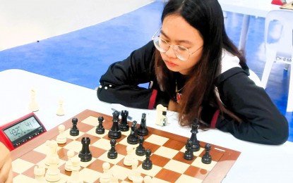 <p><strong>LEADER.</strong> Precious Eve Ferrer prepares her next move against Shaniah Francine Tamayo in Round 8 of the Queen of the North chess tournament at Ilocos Norte National High School gymnasium in Laoag City on Friday (Dec. 21, 2023). Ferrer won the in 50 moves of London System Opening to keep the lead with 7.0 points.<em> (Contributed photo)</em></p>