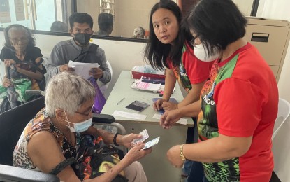 <p><strong>CASH AID.</strong> An elderly resident receives cash aid for her maintenance medicine from a social worker at the Ilocos Norte capitol in this undated photo. This year, low-income senior citizens in the province will receive food packs and other items. <em>(PNA photo by Leilanie Adriano)</em></p>