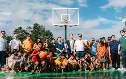 <p><strong>SPORTS ENTHUSIASTS.</strong> Wu Chenqi (center, in suit), director of the Media and Public Relations Section of the Chinese Embassy in Manila and Naga City Mayor Nelsono Legacion (to Wu's left, in white) pose with young basketball players of Liberty Village, Barangay Cararayan after the turnover ceremony of a new basketball court on Friday (Dec. 29, 2023). The sports facility was donated by the embassy through the city government. <em>(Photo courtesy of Naga City-PIO)</em></p>