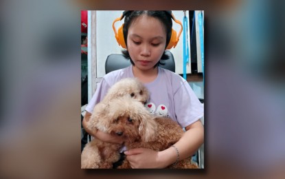 <p><strong>PROTECTED.</strong> Maricar Estor wears earmuffs and holds her pets close to make them feel secured during the New Year’s Eve revelry. According to the Department of Health, firework explosions with sound levels of 140 to 150 decibels can lead to pain and ear injuries. <em>(PNA photo by Ma. Teresa P. Montemayor)</em></p>
