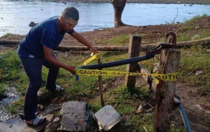 <p><strong>UNSAFE.</strong> A municipal health personnel cordons off Tuesday (Jan. 2, 2024) one of the four water pumps to prevent residents from taking drinking water after a diarrhea outbreak that left five dead in Talayan, Maguindanao del Sur since Dec. 31, 2023. The communal water pumps are situated near the Talayan River in Barangay Tamar of Talayan where locals dump their garbage and dispose of human waste, among others.<em> (Photo from Talayan MDRRMO)</em></p>