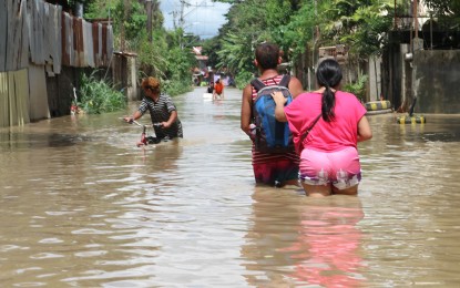 <p><strong>FLOODED.</strong> Residents of Jade Valley subdivision in Buhangin District, Davao City, wade through floodwaters on Jan. 19, 2024. The Department of Health advises the public to avoid wading or playing in flood water as this could cause leptospirosis. <em>(PNA photo by Robinson Niñal Jr.)</em></p>