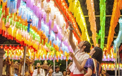 <p><strong>TOURISM REBOUND</strong>. Tourists hang a lantern at the Wat Phra That Hariphunchai in Lamphun, Thailand in this Nov. 23, 2023 photo. Lamphun Province of Thailand held a grand lantern festival at the Wat Phra That Hariphunchai, attracting tourists to hang lanterns and make wishes. <em>(Xinhua)</em></p>