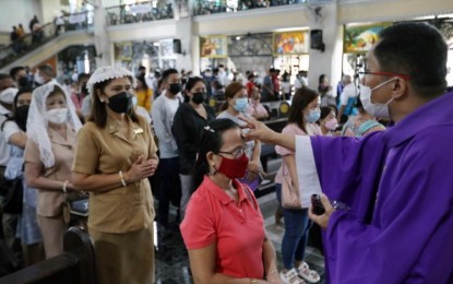 <p><strong>ASH WEDNESDAY.</strong> A Catholic priest puts ash on the forehead of an elderly woman during the observance of Ash Wednesday at the St. Peter Parish: Shrine of Leaders in Quezon City in this file photo. Ash Wednesday, which marks the start of the Lenten season, falls on Valentines Day this year. <em>(PNA photo by Joey O. Razon)</em></p>