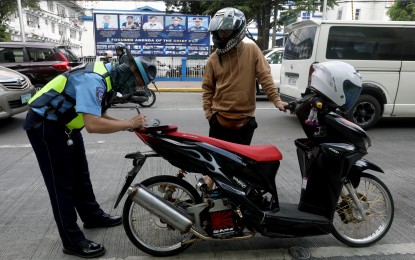 <p><strong>TRAFFIC STOP.</strong> A traffic enforcer of the Land and Transportation Office (LTO) verifies the registration and license of a motorcycle rider along United Nations Avenue in Ermita, Manila on Feb. 15, 2024. The LTO has partnered with the Metropolitan Manila Development Authority (MMDA) to make use of the agency's cameras in the National Capital Region to help catch more traffic violators. <em>(PNA photo by Yancy Lim)</em></p>