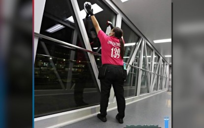 <p><strong>STEP UP.</strong> A janitorial services employee cleans the glass windows at the airport in this undated photo. The Manila International Airport Authority is in charge of their contracts, even when the private operator comes in, MIAA acting general manager Eric Ines said.<em> (Photo from NAIA's Facebook page)</em></p>