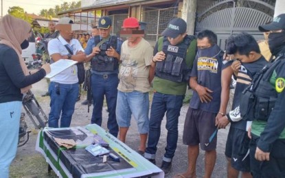 <p><strong>DRUG PEDDLERS.</strong> An anti-narcotics operative accounts for the prohibited shabu confiscated from two drug peddlers (in handcuffs) during a buy-bust in Datu Odin Sinsuat, Maguindanao del Norte. The suspects had been under surveillance for two weeks before their arrest on Monday (March 11, 2024).<em> (Photo from PDEA-BARMM)</em></p>