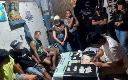 <p><strong>DRUG DEN.</strong> Russian national, Viktor Tutov (leftmost), 38, jobless, and other suspects watch as agents of the Philippine Drug Enforcement Agency conduct an onsite inventory of illegal drugs seized during the drug den dismantling operation in Barangay Basdio, Loon, Bohol on Tuesday (March 12, 2024). Anti-narcotics authorities in Cebu and Bohol confiscated PHP17 million worth of shabu in two separate sting operations. <em>(Photo courtesy of PDEA-7)</em></p>