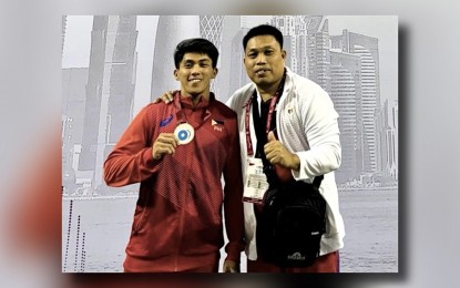 <p><strong>PROUD CEBUANO.</strong> John Febuar Ceniza (left), with national coach Christopher Bureros, shows his silver medal in the men's 71kg. category of the International Weightlifting Federation Grand Prix II in Doha, Qatar on Feb. 6, 2023. Ceniza will vie for a spot in the upcoming Paris Olympics in July via the International Weightlifting Federation World Cup in Phuket, Thailand on March 31 to April 11. <em>(Contributed photo) </em></p>