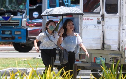 <p><strong>PROTECTED.</strong> Two pedestrians share an umbrella while crossing the intersection of Roxas Boulevard and Katigbak Parkway in Ermita, Manila on April 7, 2024. The country will continue to experience fair weather on Thursday (April 18), the weather bureau said. <em>(PNA photo by Avito Dalan)</em></p>